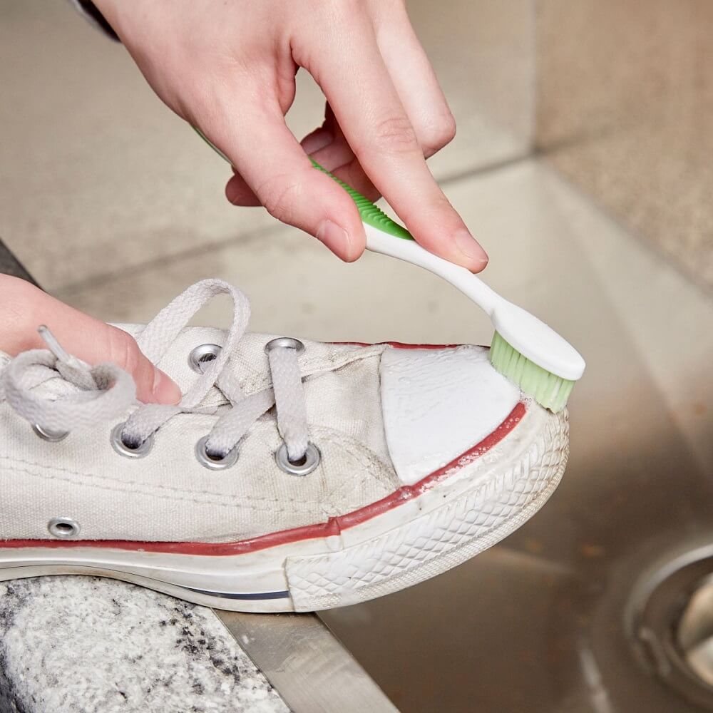 Čištění bílých plátěných bot zubním kartáčkem